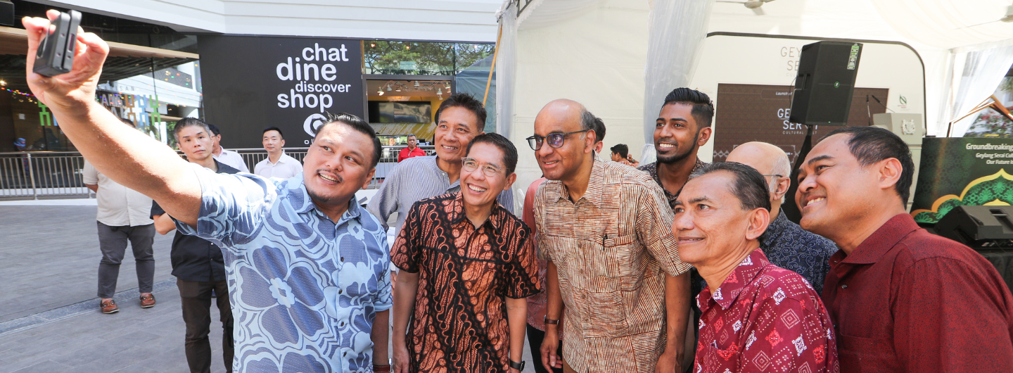 Group of men pose for a selfie outdoors; "chat dine discover shop" sign visible.
